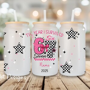 May include: Three frosted glass tumblers with bamboo lids and straws. Each tumbler features a design with a checkered star, pink stars, and the text "The Year I Survived Six Seven". The center tumbler has a pink number 6 and 7.