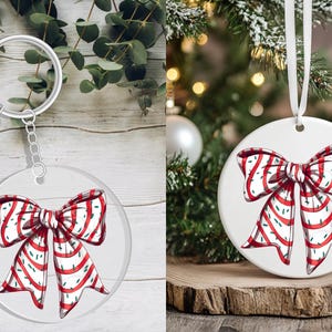 May include: A clear acrylic keychain and a white ceramic Christmas ornament, both featuring a red and white striped bow design. The keychain has a silver tassel and chain. The ornament hangs from a white ribbon.