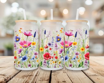 May include: Three white tumblers with a floral design featuring pink, purple, blue, yellow, and green flowers. The tumblers have a frosted finish and are topped with bamboo lids and straws.
