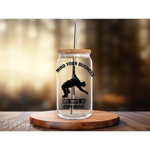 May include: A clear glass tumbler with a wooden lid and a black and white graphic that says "Mind Your Business My Wife Is Expensive".