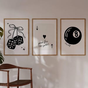 May include: Three framed art prints with a gambling theme. The prints feature black and white illustrations of dice, a playing card, and a billiard ball. The ace of hearts card has the text "good for the plot". The eight ball has the text "Lucky".