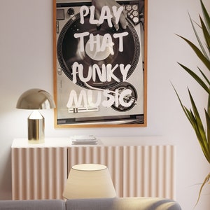 May include: A framed black and white photograph of a hand on a turntable with the text "PLAY THAT FUNKY MUSIC" written in white paint.