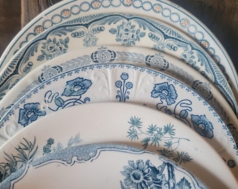 Op de afbeelding: Een stapel van vier keramische borden met diverse blauw-witte bloemen- en botanische patronen. Elk bord toont opvallende decoratieve randen, gedetailleerd lijnwerk en illustraties van bloemen, bladeren en stengels op een crèmekleurige ondergrond.
