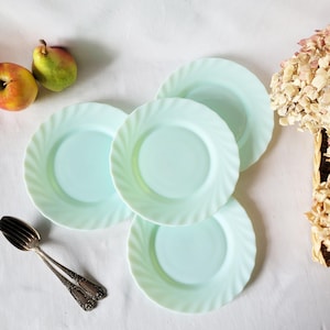 May include: Four light blue glass plates with a wavy edge. The plates are stacked on top of each other.