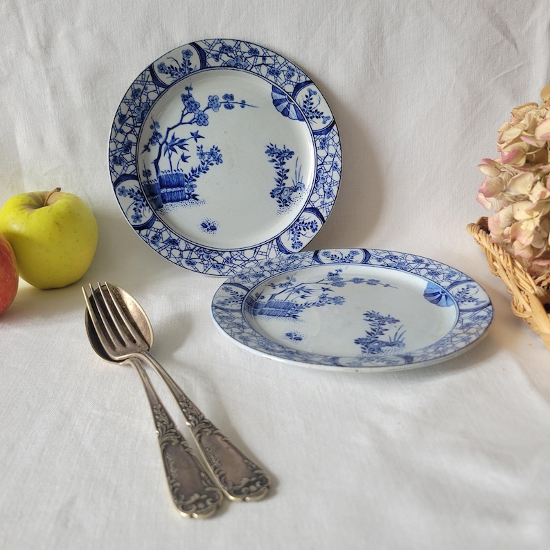 May include: Two blue and white porcelain plates with a floral design. The plates have a blue and white lattice border.