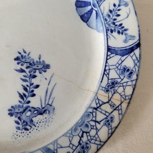 May include: A blue and white porcelain plate with a floral design. The plate has a crack in the glaze.