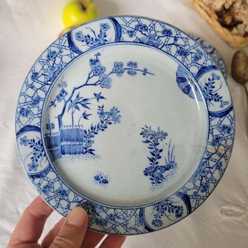 May include: A white ceramic plate with a blue and white floral design. The plate has a scalloped edge and a raised rim.