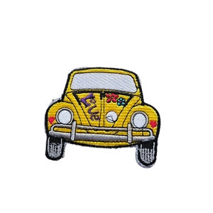 May include: Yellow Volkswagen Beetle car patch with a purple "Love" inscription and colorful flowers on the back window. The car has white headlights and a gray bumper.