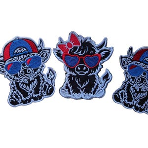 May include: Three embroidered patches featuring black Highland cattle characters. Two patches show cattle wearing blue and red baseball caps and blue sunglasses. The center patch shows a cow with a red bow and red heart-shaped sunglasses.