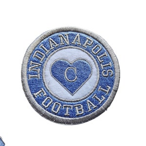 May include: Blue and silver embroidered patch with the text "Indianapolis Football" in a circle around a white heart with a blue "C" inside.