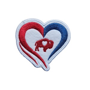 May include: Embroidered patch featuring a heart design with red and blue sections, and a small bison silhouette in the center. The patch has a white background and a white border.