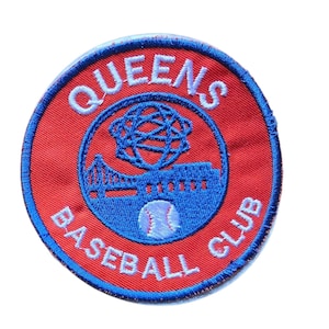 May include: A circular embroidered patch with a red background and blue border. The text QUEENS BASEBALL CLUB is stitched in white. The center features a blue graphic of a bridge, a globe-like structure, and a baseball on a blue circular field.