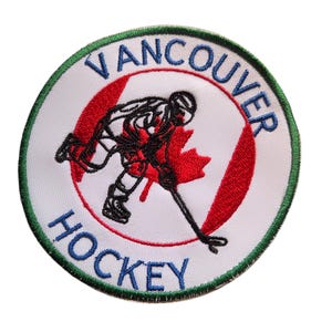 May include: Embroidered patch featuring a hockey player in action, set against a red maple leaf and stripes, with the words "Vancouver Hockey" in blue. The patch has a white background and a green border.