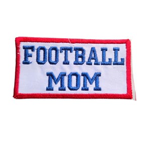 May include: Embroidered patch with the words "FOOTBALL MOM" in blue block letters on a white background. The patch has a red border.