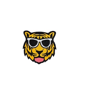 May include: A yellow and black embroidered patch of a tiger wearing white sunglasses. The tiger has a pink tongue sticking out.