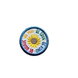May include: A round embroidered patch with a sunflower in the center and the words "Be Kind", "Be Brave", "Be True", and "Be You" surrounding the sunflower.