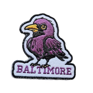 May include: Purple embroidered patch with a cartoon bird and the word "BALTIMORE" in purple lettering.