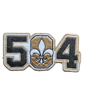 May include: A black and gold embroidered patch with the number 504 and a fleur-de-lis in the center.