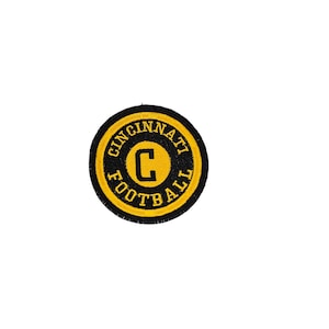 Op de afbeelding: Een ronde zwarte en gele patch met de tekst "Cincinnati Football" en een grote "C" in het midden.