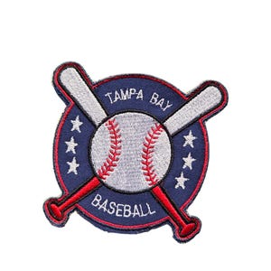 May include: A circular embroidered patch featuring a baseball with red stitching centered over two crossed silver baseball bats. The dark blue background displays the white text TAMPA BAY and BASEBALL with three white stars on each side.