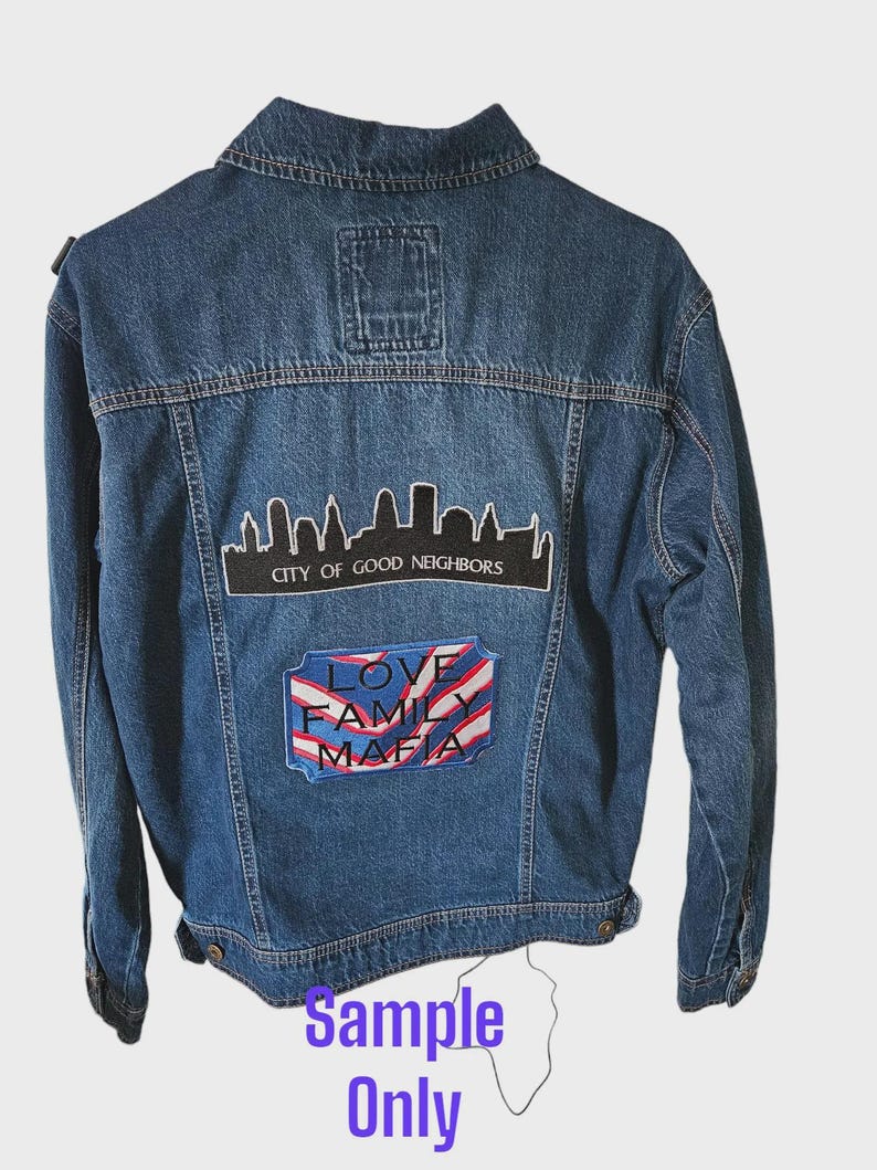 May include: A blue denim jacket featuring a cityscape patch and a patch with the words "LOVE FAMILY MAFIA". The jacket has a classic design with button closures and pockets. The text "Sample Only" is at the bottom.