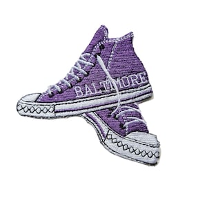 May include: Purple embroidered patch of a pair of high-top sneakers with the word "BALTIMORE" stitched on the side.