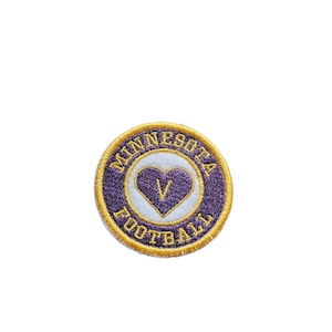 May include: Purple and gold embroidered patch with a white heart containing a purple "V" inside. The text "MINNESOTA FOOTBALL" is around the heart.