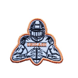May include: An orange and white embroidered patch of a football player in a helmet holding a football. The player's jersey says "CHICAGO".