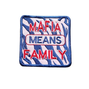 May include: A square embroidered patch featuring a light pink background with a dark blue tiger stripe pattern. The text MAFIA is in red, MEANS is in blue inside a white oval, and FAMILY is in red. The patch has a dark blue stitched border.