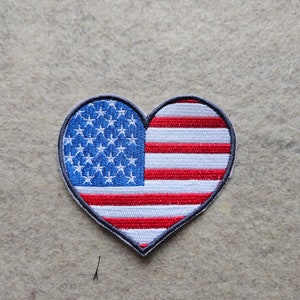 May include: A heart-shaped patch with the American flag design. The patch is embroidered with red and white stripes and blue stars.