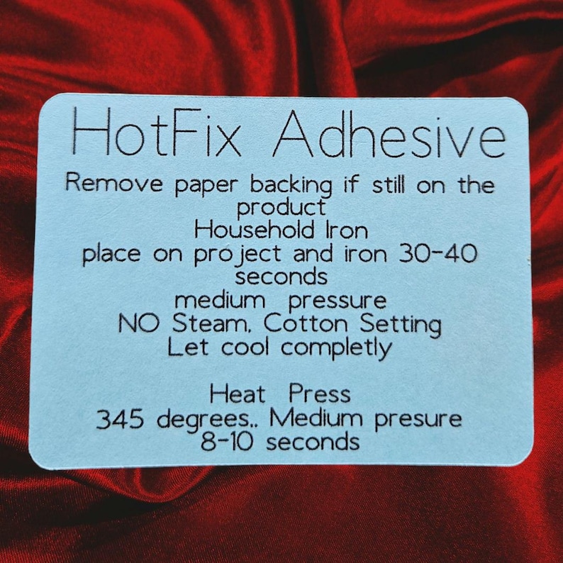 May include: Blue instruction card with the text "HotFix Adhesive" and instructions for using a household iron or heat press to apply the adhesive. The instructions include the temperature and time settings for both methods.