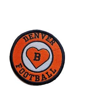 May include: Orange and black embroidered patch with the text "DENVER FOOTBALL" around a white heart with a black "B" inside.
