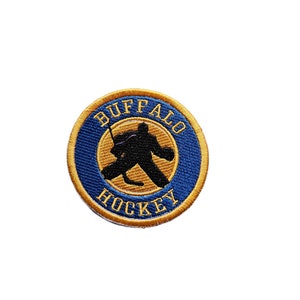 May include: Embroidered patch featuring a hockey goalie silhouette in black. The patch has a blue background with gold trim and the words "BUFFALO HOCKEY" in gold lettering, creating a circular design.