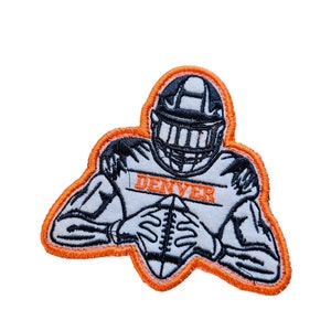 May include: An orange and white embroidered patch of a football player in a helmet holding a football. The patch says "DENVER" in white letters.