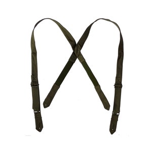 Puede incluir: Un par de tirantes verdes con clips metálicos. Los tirantes están cruzados en la espalda y tienen un diseño sencillo.