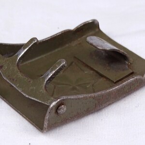 May include: A green metal belt buckle with a star design. The buckle has a metal tongue and a spring-loaded closure.
