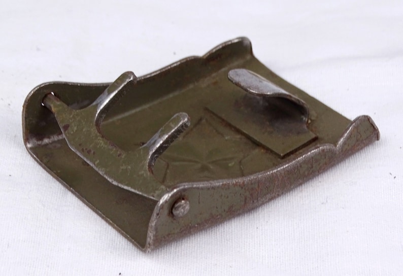 May include: A green metal belt buckle with a star design. The buckle has a metal tongue and a spring-loaded closure.