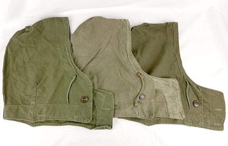 May include: Three olive green canvas hooded vests with drawstrings and buttons.
