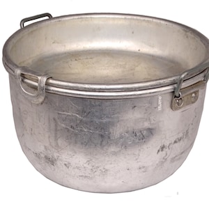 Peut inclure: Une casserole de camping en aluminium argenté avec deux poignées. La casserole a un fond arrondi et est faite d'un métal durable.