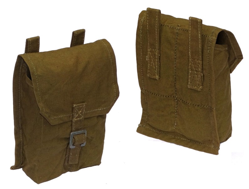May include: Two olive-green canvas pouches with flap closures and metal buckles. The pouches have stitched detailing and belt loops on the back. One pouch is shown from the front and the other from the back.