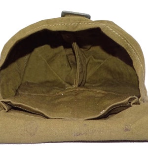 May include: An olive drab canvas pouch with a rectangular shape and a hinged flap. The interior is visible, showing a matching olive drab lining. A metal clasp secures the flap. The pouch appears to be vintage or military-style.