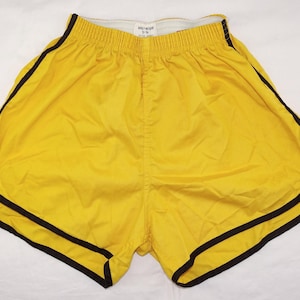 Pu&ograve; includere: Pantaloncini sportivi gialli con bordatura nera. I pantaloncini hanno un elastico in vita e un design retr&ograve; classico. Sono realizzati in un materiale leggero, perfetti per la corsa o altre attivit&agrave; sportive. I pantaloncini sono di colore giallo brillante.