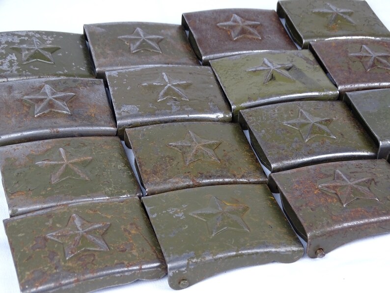 May include: A pile of 15 vintage metal belt buckles with a star design. The buckles are a dark green color with rust spots and are arranged in a staggered pattern.