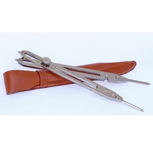 May include: A silver compass with a brown leather case. The compass has a rotating dial and two points.