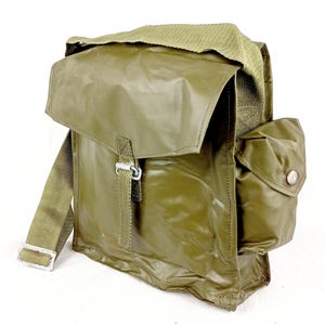 Puede incluir: Bolso de hombro de estilo militar verde oliva con cierre de solapa y un bolsillo lateral. El bolso cuenta con una correa de hombro tejida y una hebilla de metal. El bolso está hecho de un material brillante e impermeable.