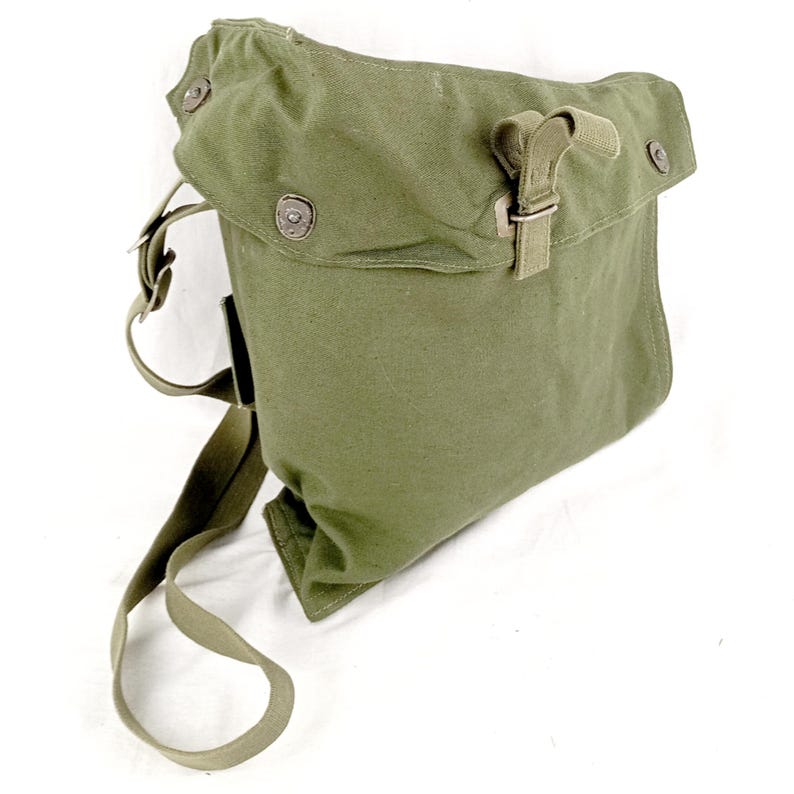 May include: A green canvas shoulder bag with a flap closure and a buckle. The bag has a long adjustable strap and is made of a durable material.