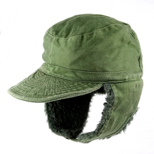 Könnte beinhalten: Eine grüne Militärkappe aus Canvas mit Ohrenschützern, die mit Kunstfell gefüttert sind. Die Kappe hat eine breite Krempe und eine strukturierte Krone.