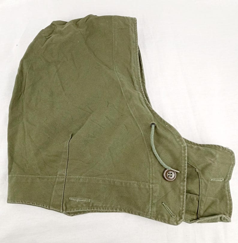 May include: A green hooded vest with a drawstring and a button closure. The vest is made of a thick, durable fabric.