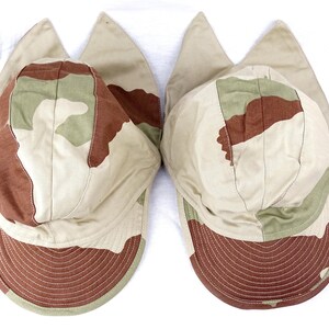 May include: Two camouflage-patterned baseball caps with ear flaps. The caps are beige, brown, and green with a brown brim.