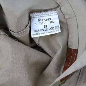 May include: A beige fabric label with the text "SEYNTEX B - TIELT - 2001 57" and symbols for washing instructions. The label also says "trait&eacute;s anti-moustiques".